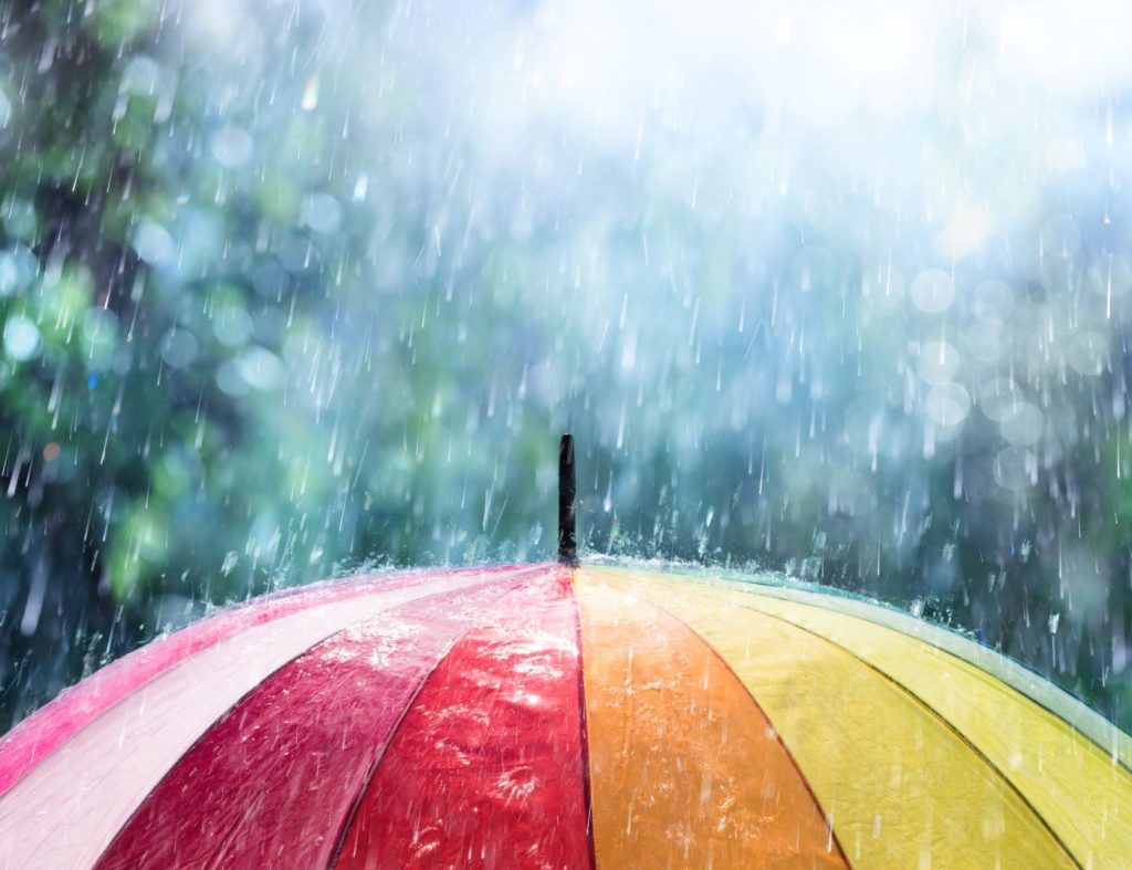 A rainbow colored umbrella in the rain.